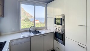 A compact kitchen with a window, a dishwasher, a sink, and built-in ovens. - Sunny Side by Atlantic Holiday (Madalena do Mar)
