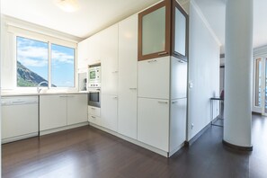 Una cocina moderna con armarios blancos, horno integrado y microondas.