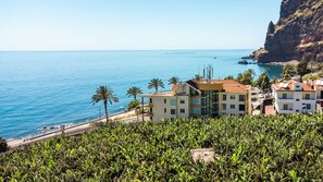 Un bâtiment situé sur la côte, offrant une vue sur la mer et un promontoire rocheux.
