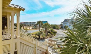 A balcony with a view of a landscaped area, palm trees, and buildings in the background.