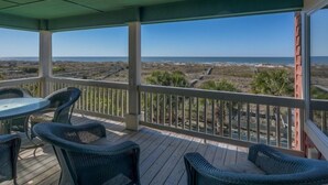 A covered outdoor area with a view of the beach, featuring a table and chairs.