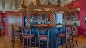 A kitchen with a central island, wooden bar stools, and a ceiling with exposed beams.