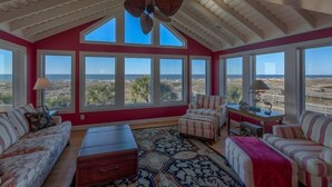 A spacious room with large windows, a ceiling fan, and a view of the landscape.