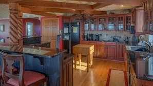 A spacious kitchen with wooden beams, a central island, and a dining area with a chair.