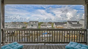 A covered deck with a view of houses and a boat in the background.