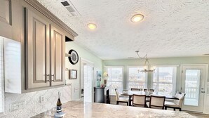 A kitchen with a marble countertop, wooden cabinets, a dishwasher, and a dining area with a chandelier.