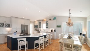 Una cocina amplia con una isla grande, muebles blancos y una araña.