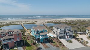 Zona residencial costera con propiedades frente al mar, incluyendo una casa grande con piscina y un muelle que se adentra en el agua.