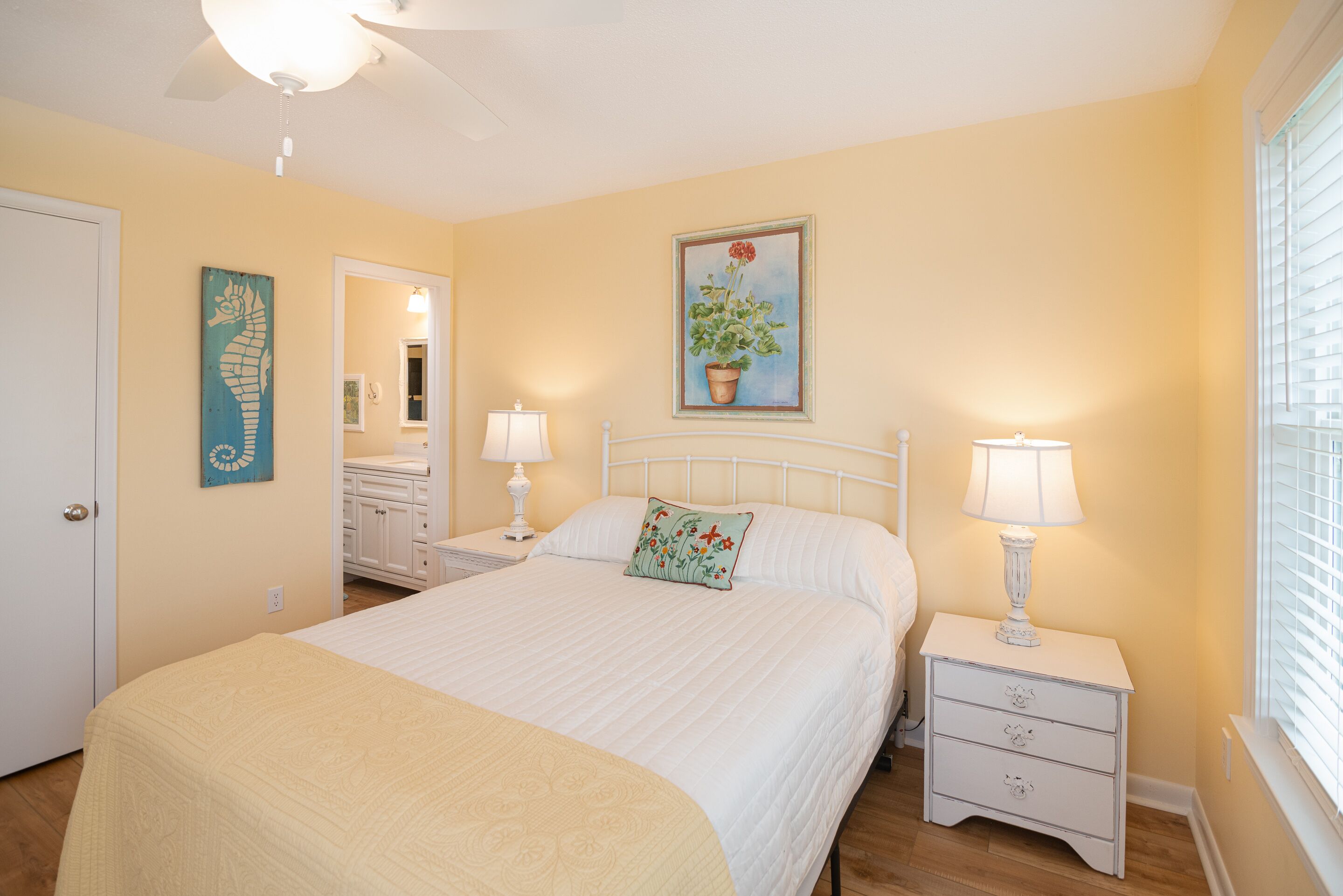 A bedroom with a bed, two bedside tables with lamps, a door, and a painting on the wall.