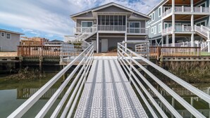 A waterfront property with a dock leading to a house with multiple balconies and a covered deck.