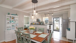 A spacious kitchen with white cabinets, a wooden dining table, and green chairs.