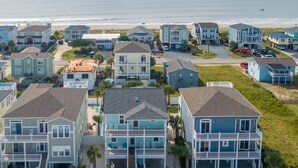 A coastal residential area with beachfront properties featuring balconies, a parking area, and a view of the ocean. - Carolina in My Mind - Private pool, walking distance to beach, and more! (Holden Beach)