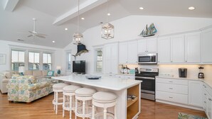 A spacious kitchen with a large island, white cabinetry, and a modern ceiling fan. - Carolina in My Mind - Private pool, walking distance to beach, and more! (Holden Beach)
