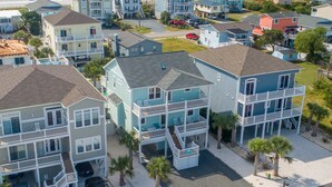 A coastal residential area with multi-story houses, a beach in the background, and a clear sky. - Carolina in My Mind - Private pool, walking distance to beach, and more! (Holden Beach)