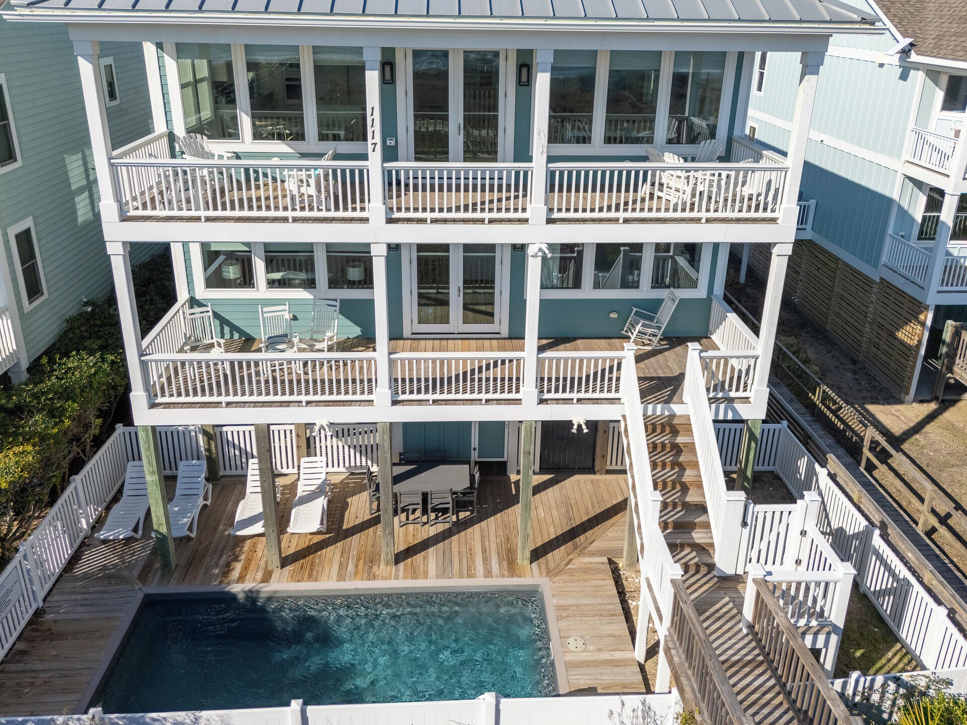 Una casa de varios pisos con piscina, balcones y mobiliario de exterior.