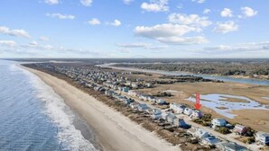Zona residencial costera con casas a lo largo de la playa, un río y un letrero que dice 'HOME'.