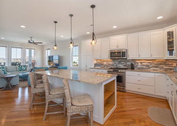 Enjoy cooking in this well-equipped kitchen with a central island and bar stools, featuring a microwave, oven, and ample cabinetry.