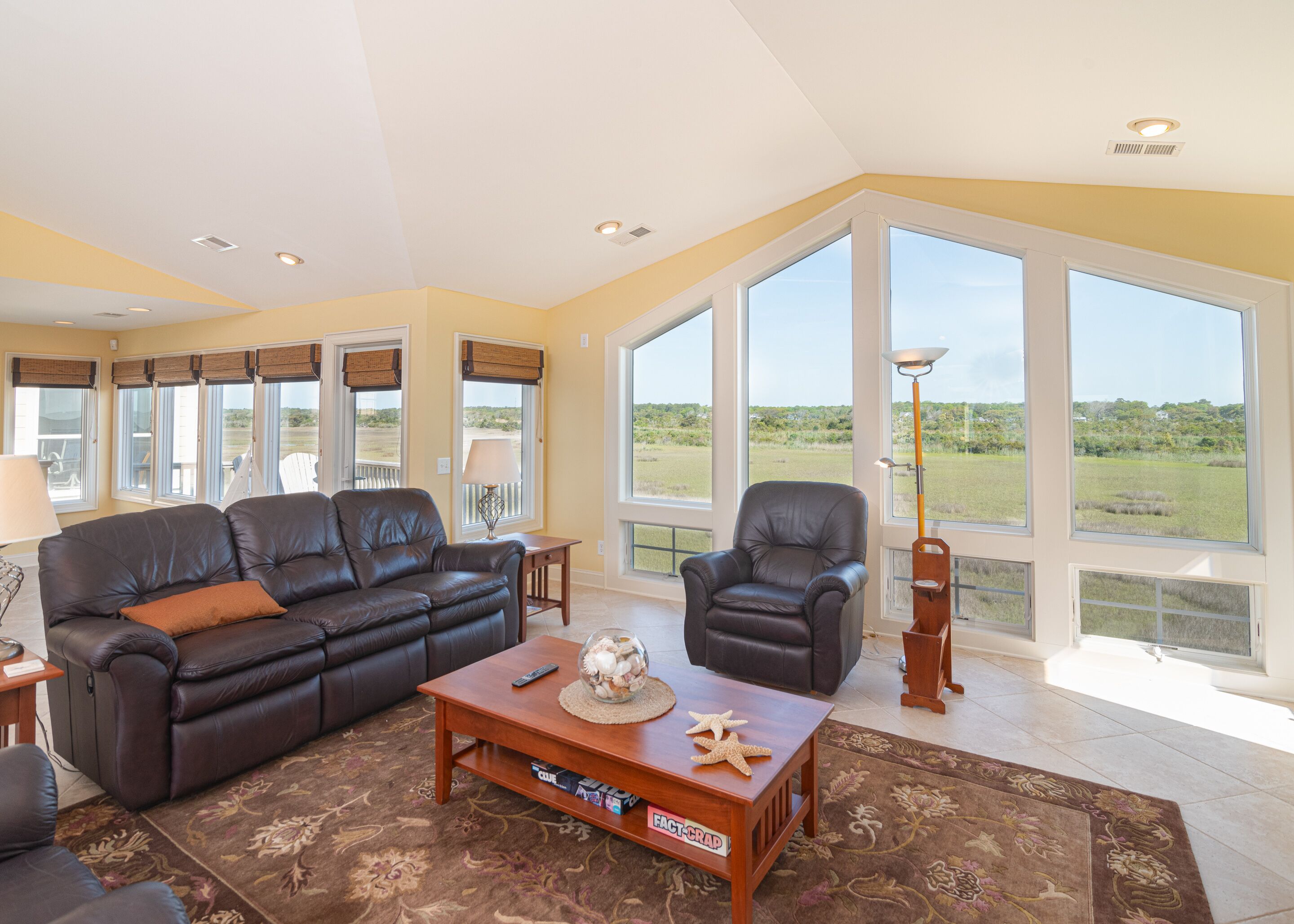 A spacious living room with a leather sofa, a coffee table, and a view of the outdoors.