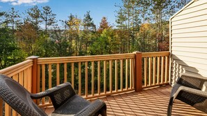 A wooden deck with wicker chairs, overlooking a forested area with autumn foliage. - Modern Retreat with Stunning Views. Holiday Valley across the Street! Sleeps 8 (Ellicottville)