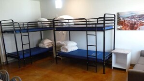 A dormitory room with bunk beds, a small table, and a couch. - Bunkhouse 3A With Cold A/C (La Verkin)