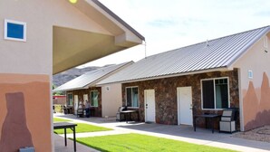 A building with a stone facade, multiple doors, and outdoor seating areas. - Bunkhouse 3A With Cold A/C (La Verkin)