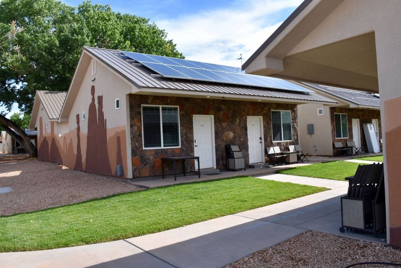 A building with a stone facade, solar panels on the roof, and a well-maintained lawn.