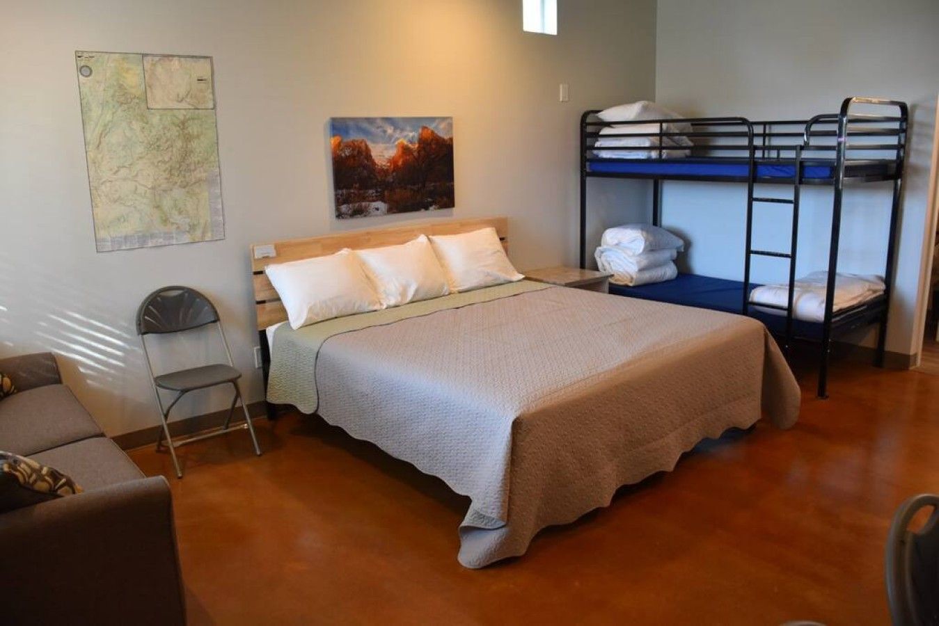 A room with a bed, bunk beds, a map on the wall, and a chair.