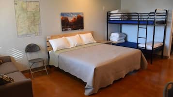 A room with a bed, bunk beds, a map on the wall, and a chair.