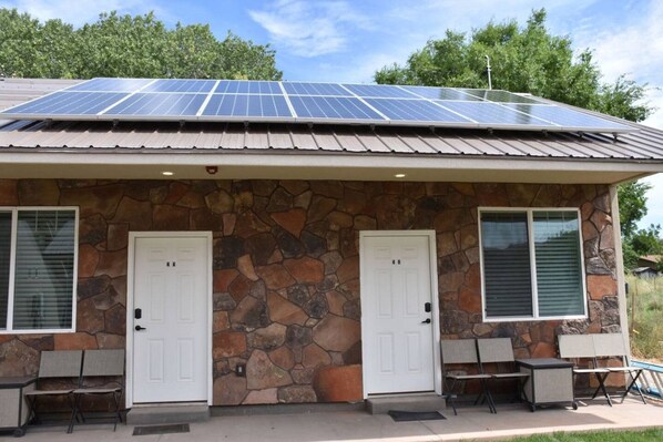 Um edifício com fachada de pedra, duas portas brancas e um conjunto de painéis solares no telhado.