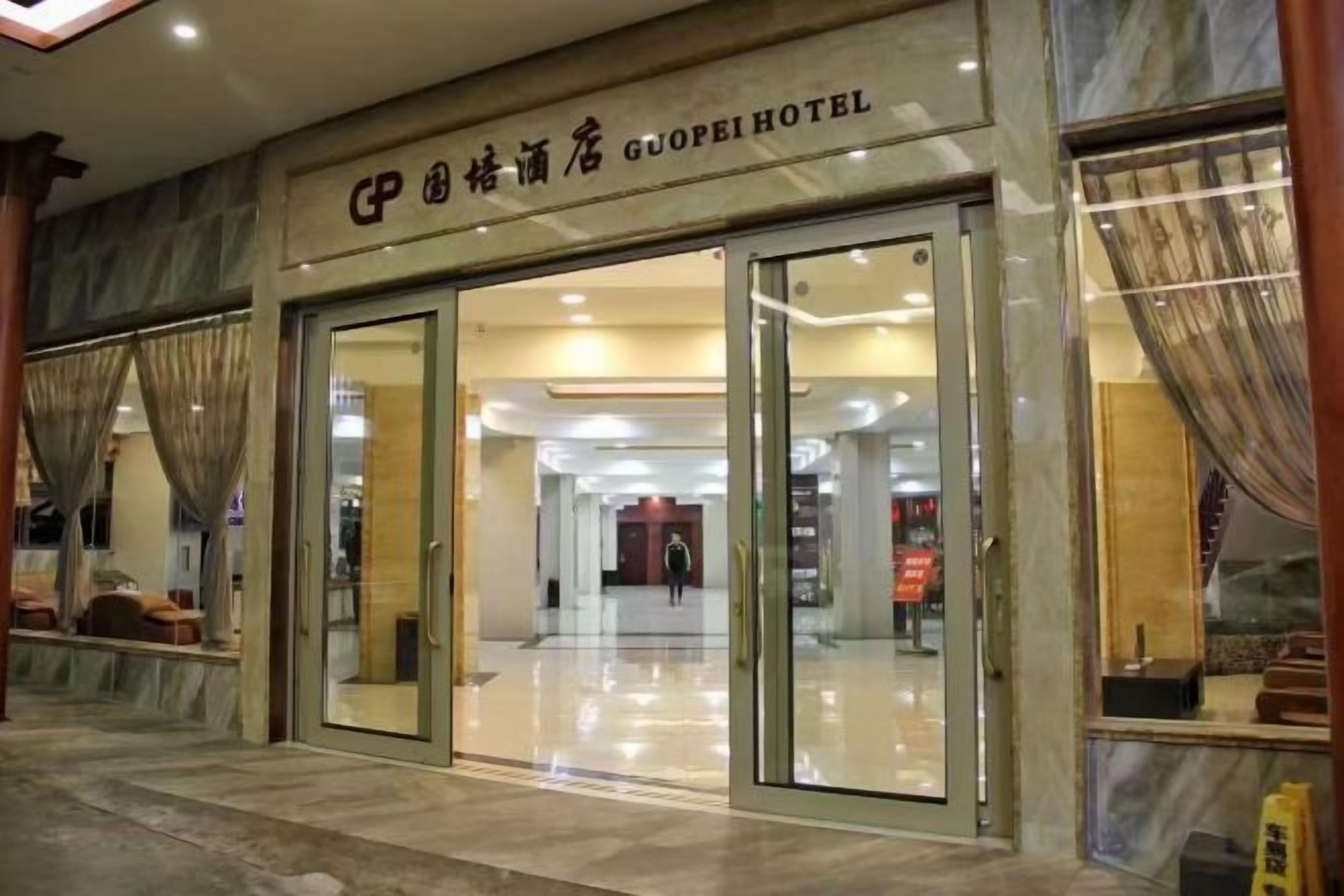 A hotel entrance with a glass door, a sign above the door, and a view into the interior.
