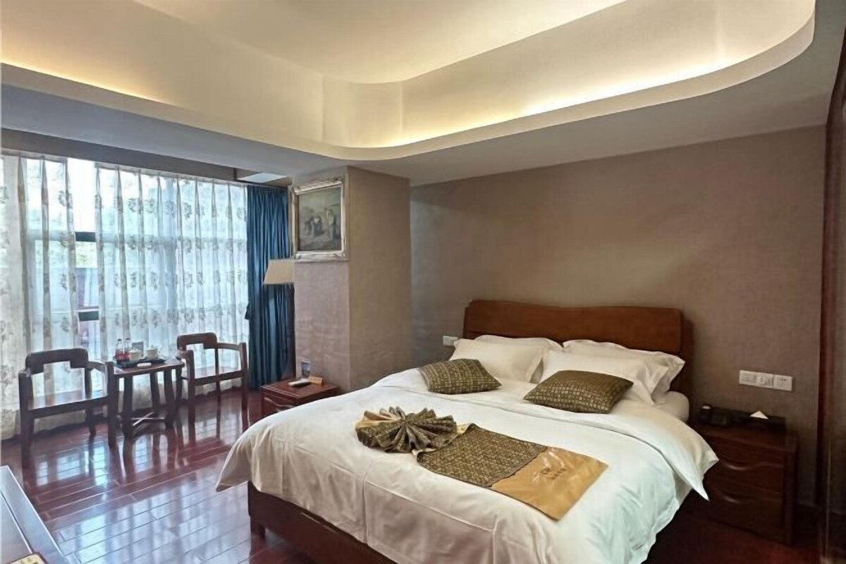 Habitación de hotel con una cama grande, un escritorio, sillas y vistas por la ventana.