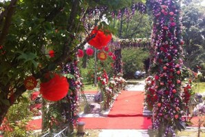 Un sendero con alfombra roja, rodeado de follaje y decoraciones florales.