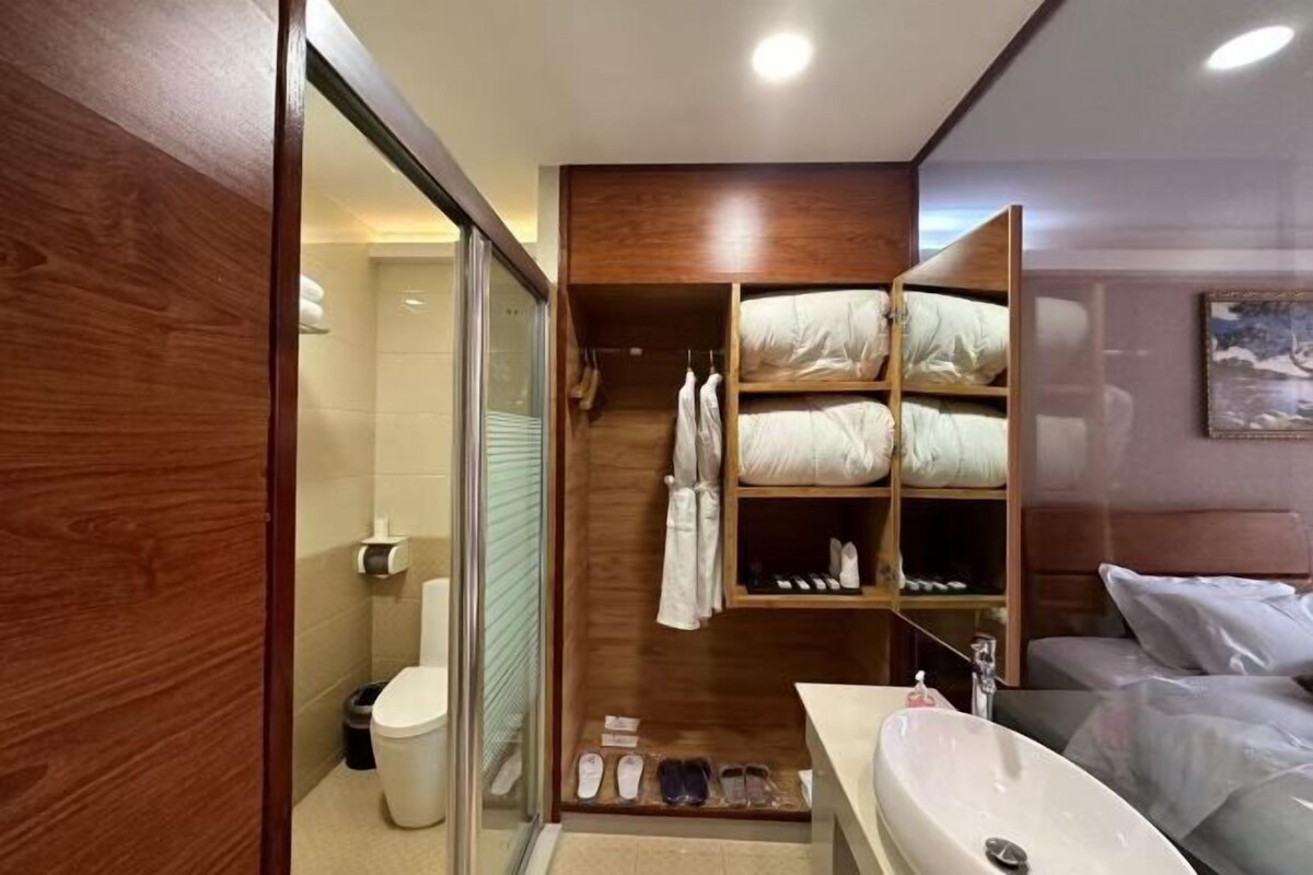 Un baño moderno con cabina de ducha de vidrio, un tocador empotrado con un lavamanos grande y un vestidor con estantes para almacenamiento.
