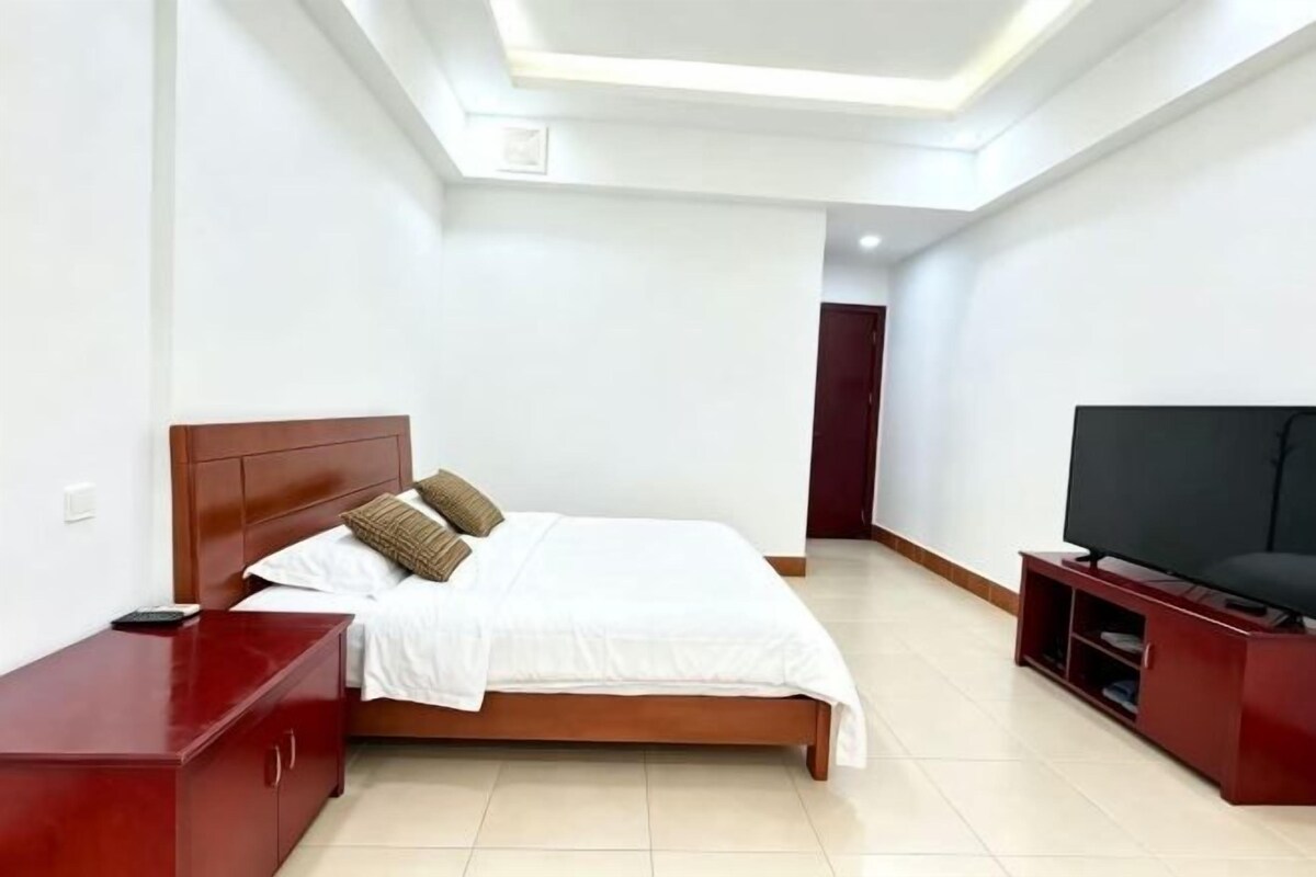 A bedroom with a bed, a TV, and a nightstand.