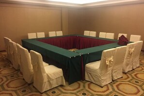 A conference room with a rectangular table surrounded by chairs, a red tablecloth, and white chair covers. - Pu'er Guopei Hotel (Pu'er)