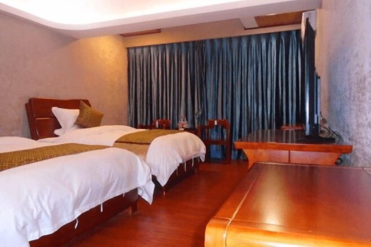 Una habitación de hotel con dos camas, una mesa de madera y un televisor.