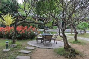 An outdoor seating area with a table and chairs, surrounded by a garden with various plants and a small pond. - Pu'er Guopei Hotel (Pu'er)