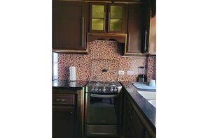 Kitchen equipped with a gas stove, oven, and sink, featuring a colorful mosaic backsplash and ample countertop space.