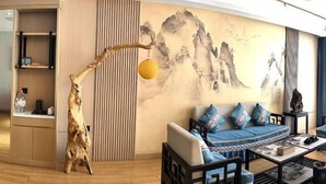 Uma sala de estar moderna com um sofá, mesa de centro e elementos decorativos como uma escultura de árvore e um adorno pendurado.