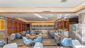Um restaurante com várias mesas e cadeiras, um balcão com cardápio e elementos decorativos nas paredes.