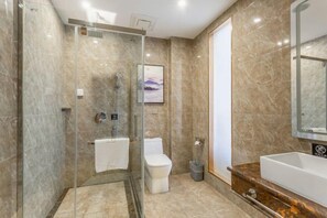 Une salle de bain moderne avec une douche à parois de verre, des toilettes blanches et un sol carrelé en marbre.