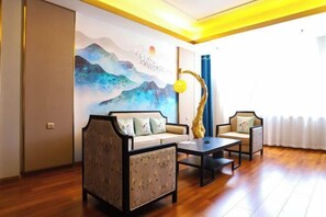 A living room with a sofa, armchair, and coffee table, a painting on the wall, and a window with curtains.