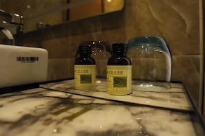 Un baño con encimera de mármol, dos botellas de loción y un recipiente azul.