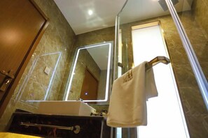 Un baño con un espejo grande, un perchero y un lavamanos.