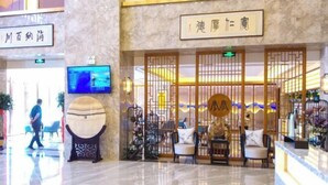 Um hall de hotel com uma mesa de recepção, um globo decorativo grande e divisórias no estilo tradicional chinês.