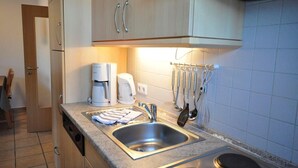 A modern kitchen with stainless steel appliances, a sink, and a coffee maker.