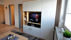 A modern living room with a flat-screen TV, built-in shelves, and a small table with a metal tray.
