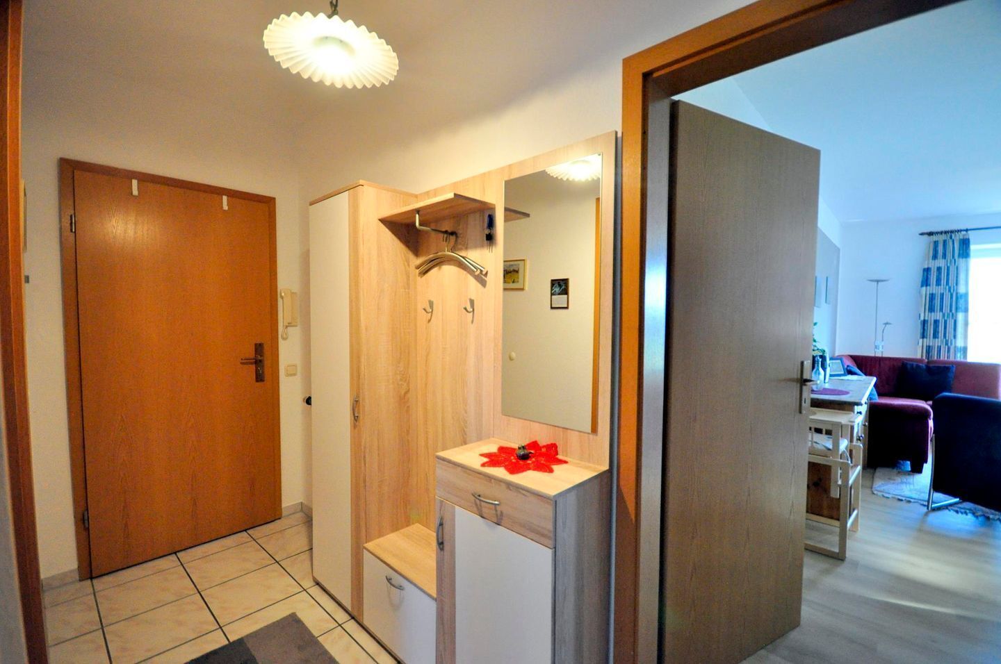 Ein kleines Badezimmer mit einem Holzkosmetikschrank, einem Spiegel und einer Duschkabine.
