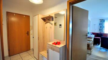 Ein kleines Badezimmer mit einem Holzkosmetikschrank, einem Spiegel und einer Duschkabine.