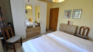 Ein Schlafzimmer mit Bett, Kleiderschrank, Stuhl, Kommode und einer Tür.